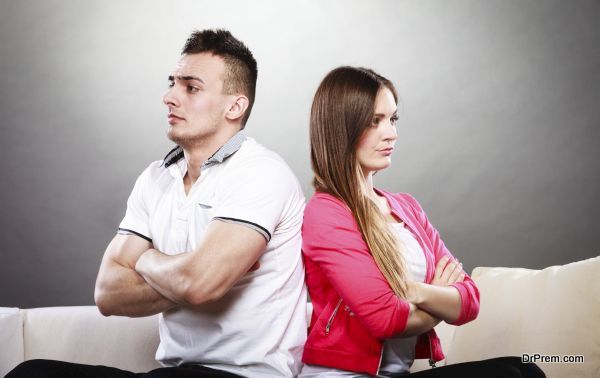 Young couple after quarrel sitting on sofa back to back