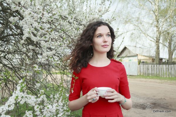 Daydreaming attractive brunette girl at spring fruit tree in white bloom