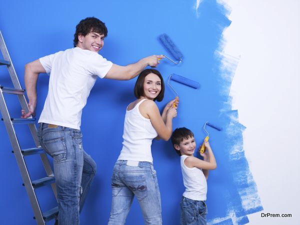 Happy young family with little son painting the wall