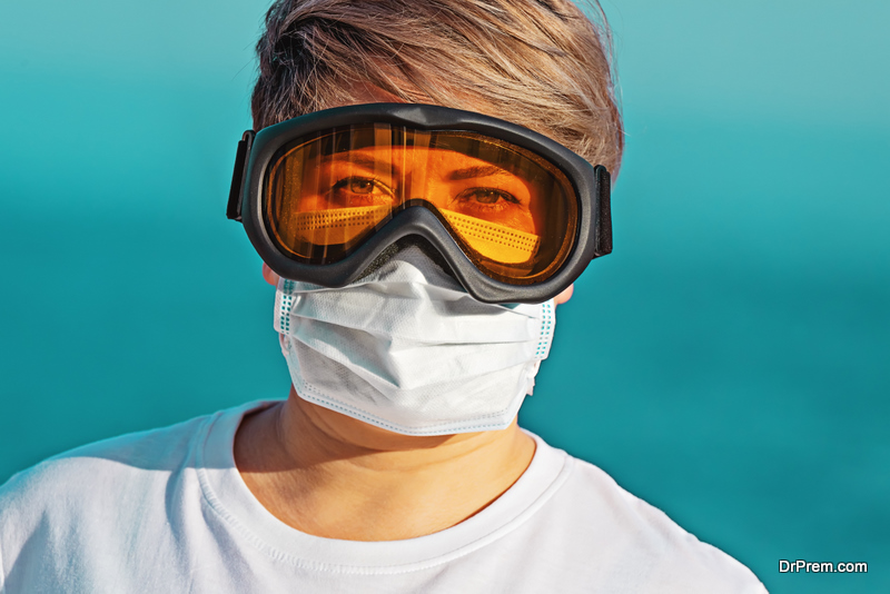 Woman in protective goggles and surgical face mask