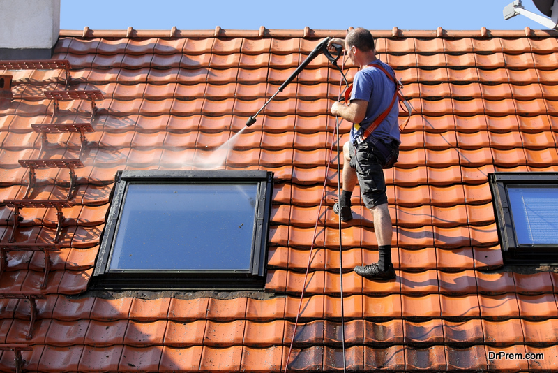 Worker is cleaning the roof and rainwater gutter with high pressure