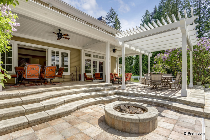 Lovely outdoor deck patio space with white pergola, fire pit in the backyard of a luxury house.