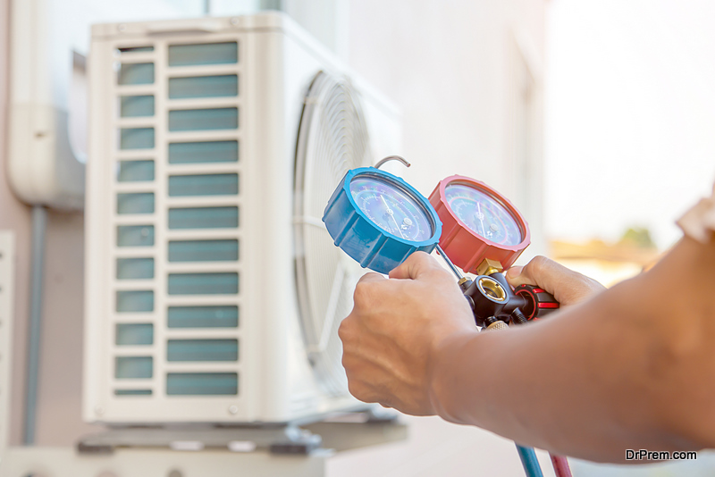 The hands of Technician are using a measuring tool to check Vacuum pump evacuates air of air conditioner.